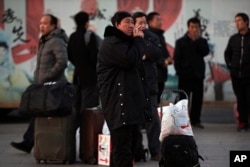 A migrant worker smokes as others wait for their trains at the Beijing railway station in Beijing, Monday, Jan. 21, 2019. China's economic growth hit a three-decade low in 2018.