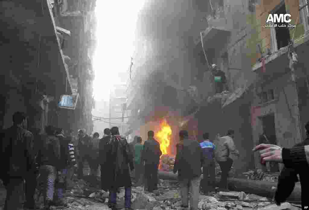 This citizen journalism image provided by Aleppo Media Center shows Syrians gathering around damaged buildings while others try to extinguish fires following a government airstrike in Aleppo, Dec. 15, 2013.