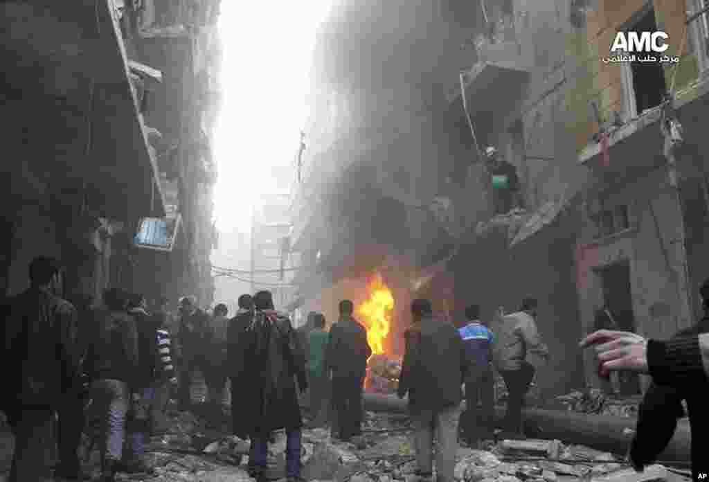 This citizen journalism image provided by Aleppo Media Center shows Syrians gathering around damaged buildings while others try to extinguish fires following a government airstrike in Aleppo, Dec. 15, 2013. 