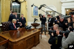FILE - President Donald Trump hands over his pen after signing his first executive order in the Oval Office of the White House in Washington, Jan. 20, 2017. Emoluments have figured prominently in discussions about the new president and his administration since his inauguration.