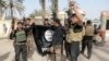 FILE - Iraqi security forces celebrate as they hold a flag of the Islamic State group they captured in Ramadi, Iraq. 