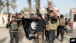 FILE - Iraqi security forces celebrate as they hold a flag of the Islamic State group they captured in Ramadi, 115 kilometers (70 miles) west of Baghdad, Iraq, Jan. 19, 2016.