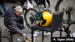 Zheng, a Chinese delivery worker, repairs his bike on a New York sidewalk.