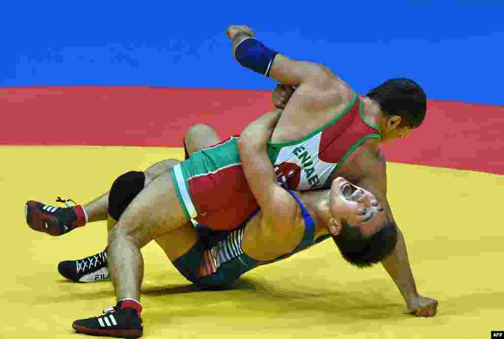 South Korea's Lee Seungchul (BLUE) competes in a bout against Uzbekhistan Jamshid Kenjaev (RED) in the men's freestyle 61kg wrestling round 1 event during the 2014 Asian Games at the Dowon Gymnasium in Incheon, South Korea.