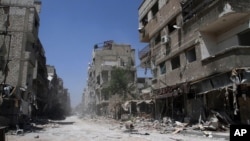 In this photo taken during a Syrian government-led media tour, buildings damaged during battles between Syrian troops and rebels stand along an empty street in Mleiha, about 10 kilometers (6 miles) southeast of downtown Damascus, Syria, Aug. 15, 2014. 