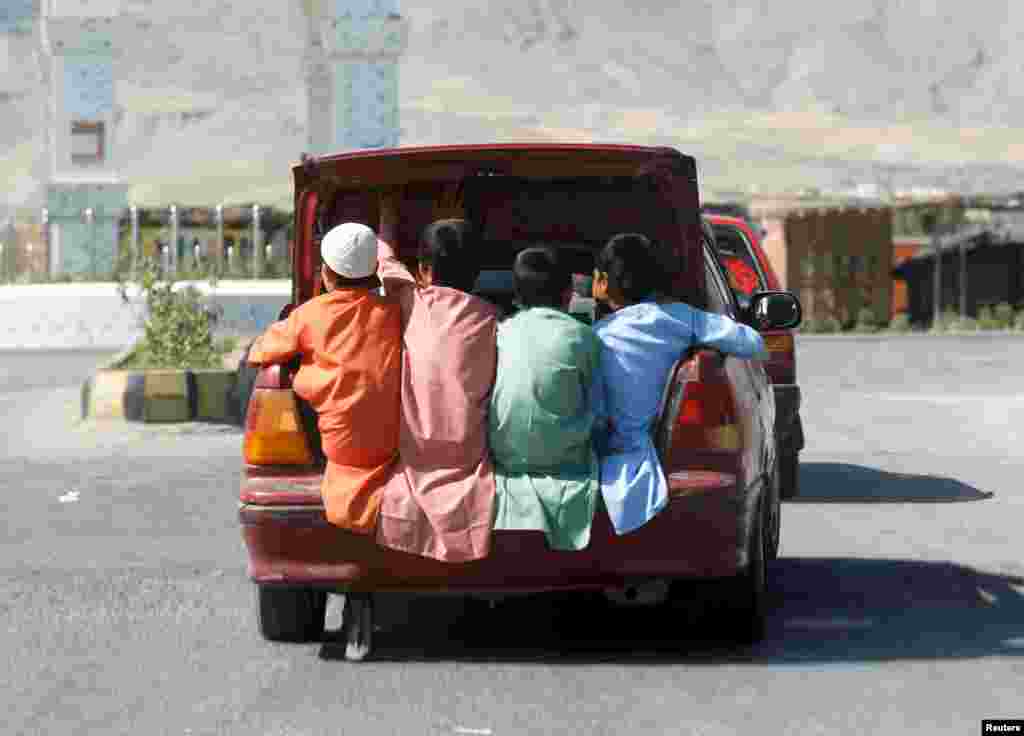 Boys travel in the trunk of a car during Eid al-Fitr, a Muslim festival marking the end the holy fasting month of Ramadan, in Laghman province, Afghanistan.