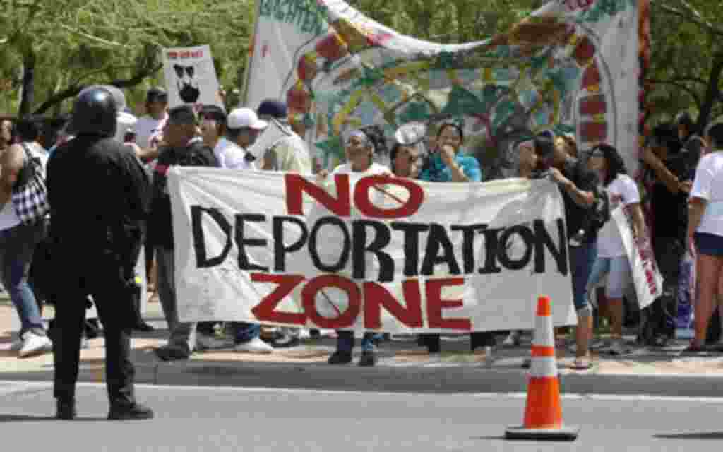 Protesters, against SB 1070, hold signs up in front of the Phoenix courthouse in Phoenix, Arizona, July 29, 2010. Arizona brought in a weakened anti-immigration law on Thursday after a U.S. court blocked its most intrusive provisions and analysts said the