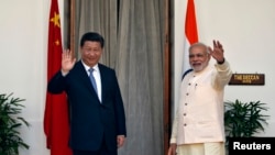 India's Prime Minister Narendra Modi, right, and China's President Xi Jinping wave to the media during a photo opportunity ahead of their meeting at Hyderabad House in New Delhi, Sept. 18, 2014. 