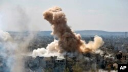 FILE - In this photo released by the Syrian official news agency SANA, smoke rises after Syrian government airstrikes and shelling hit in Hajar al-Aswad neighborhood held by Islamic State militants, southern Damascus, April 22, 2018.