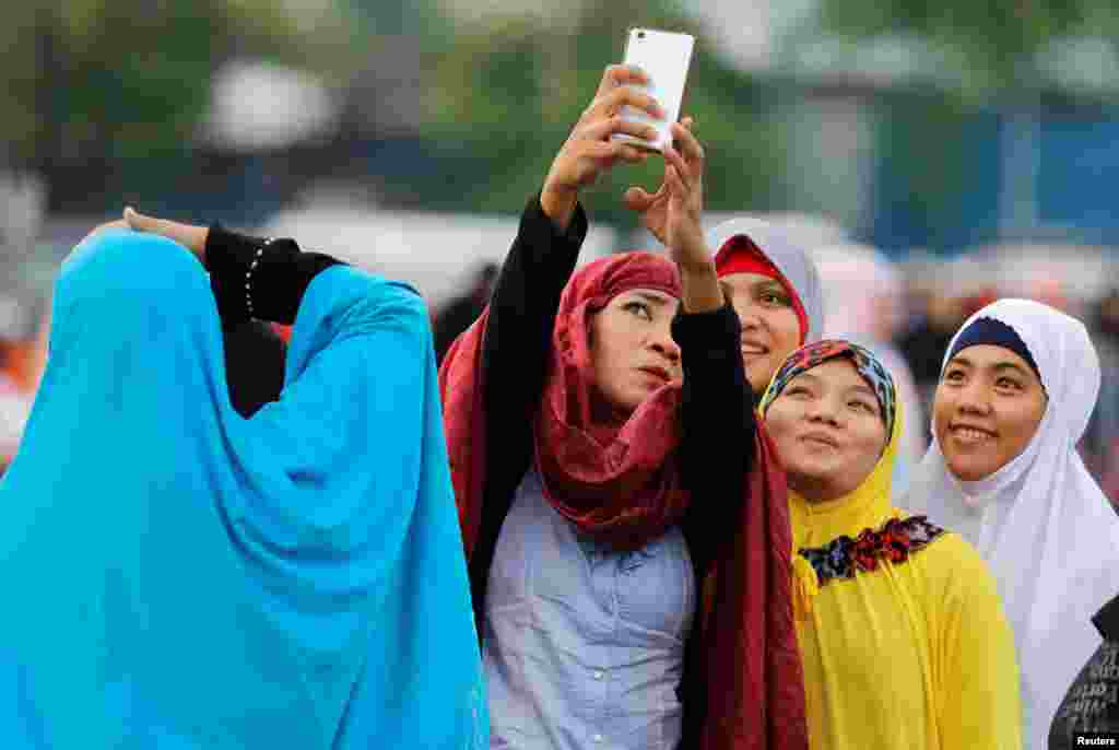 Beberapa perempuan Muslim Filipina berswafoto sebelum salat Ied di Luneta Park, Filipina, Jumat, 15 Juni 2018. (Foto: Reuters)