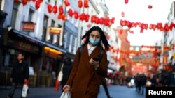 Una mujer usa una máscara protectora camina en el distrito de Chinatown, en Londres, Gran Bretaña, el 2 de marzo de 2020. 