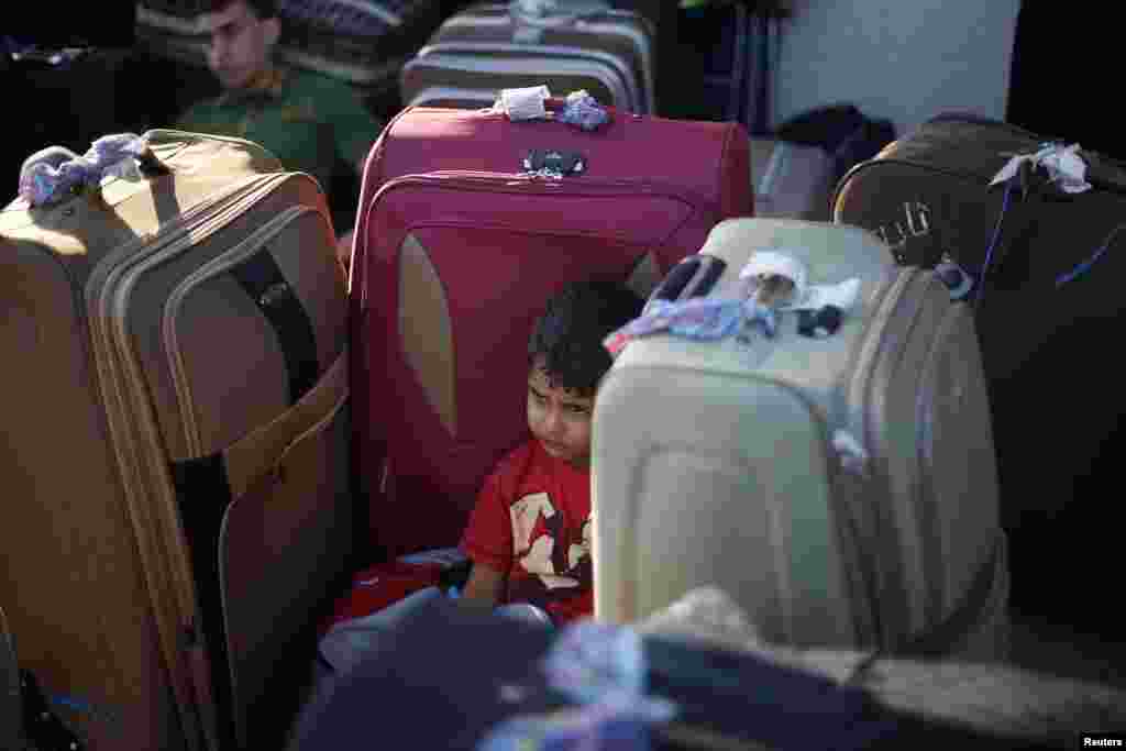 A Palestinian boy rests among suitcases as he waits to cross into Egypt at Rafah crossing between Egypt and the southern Gaza Strip. Egypt reopened its border crossing with the Gaza Strip on Saturday after four days of closure.