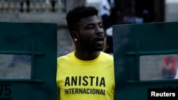 FILE - An Amnesty International activist shouts slogans in Rio de Janeiro, Brazil, April 1, 2014.
