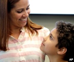 Lidia Karine Souza and her son Diogo De Olivera Filho smile at each other at the Mayer Brown law firm during a news conference shortly after Diogo was reunited with his mother, June 28, 2018, in Chicago.