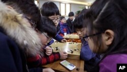 Elementary school children watch a smartphone screen showing the live broadcast of the Google DeepMind Challenge Match between Google's artificial intelligence program, AlphaGo, and South Korean professional Go player Lee Sedol, at Lee's Baduk Center in Seoul, South Korea, Tuesday, March 15, 2016. 