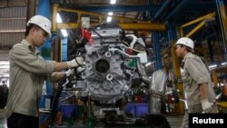 FILE - Men work with an engine at automaker Ford Vietnam's factory in Vietnam's northern Hai Duong province, outside Hanoi June 27, 2014. 