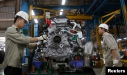 FILE - Men work with an engine at automaker Ford Vietnam's factory in Vietnam's northern Hai Duong province, outside Hanoi June 27, 2014.