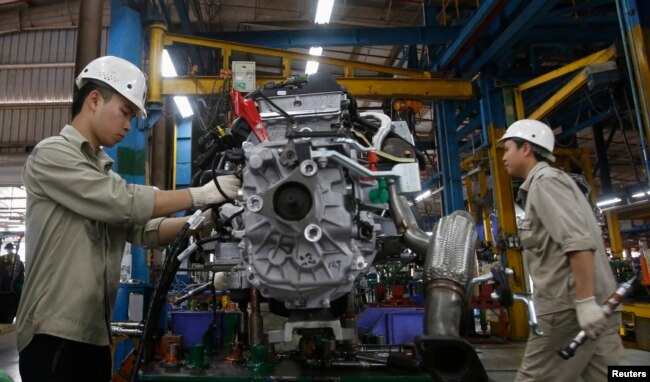FILE - Men work with an engine at automaker Ford Vietnam's factory in Vietnam's northern Hai Duong province, outside Hanoi June 27, 2014.