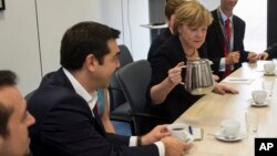 Perdana Menteri Yunani Alexis Tsipras (kiri) dan Kanselir Jerman Angela Merkel pada pertemuan Presiden Komisi Eropa Jean-Claude Juncker dan Presiden Perancis Francois Hollande sebelum pertemuan para pemimpin zona euro di Brussels, Selasa (7/7).