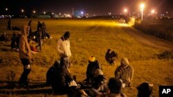 Migrants wait next to the Eurotunnel area as they attempt to access the Channel Tunnel, in Calais, northern France, Wednesday, July 29, 2015.