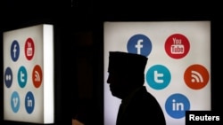 Seorang pria berjalan di depan logo-logo media sosial di Jakarta Convention Center, Jakarta, 16 Mei 2016. (Foto: Reuters)
