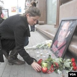 Seorang wanita Rusia meletakkan buah apel di dekat foto Steve Jobs di luar gerai Apple di Moskow (6/10).