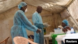 FILE - Health workers take blood samples for Ebola virus testing at a screening tent in the local government hospital in Kenema, Sierra Leone, June 30, 2014.