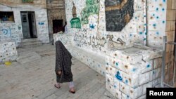 FILE - A Palestinian woman walks outside her home, next to a house (R) purchased by Jewish settlers, in the mostly Arab neighborhood of Silwan in east Jerusalem, October 2014.
