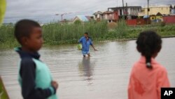 A man wades through flood water on his way to a shop in Antananarivo, Madagascar, Monday, Jan. 24, 2022. Tropical storm Ana has caused widespread flooding in Madagascar, including in the capital city, causing the deaths of 34 people and displacing more th