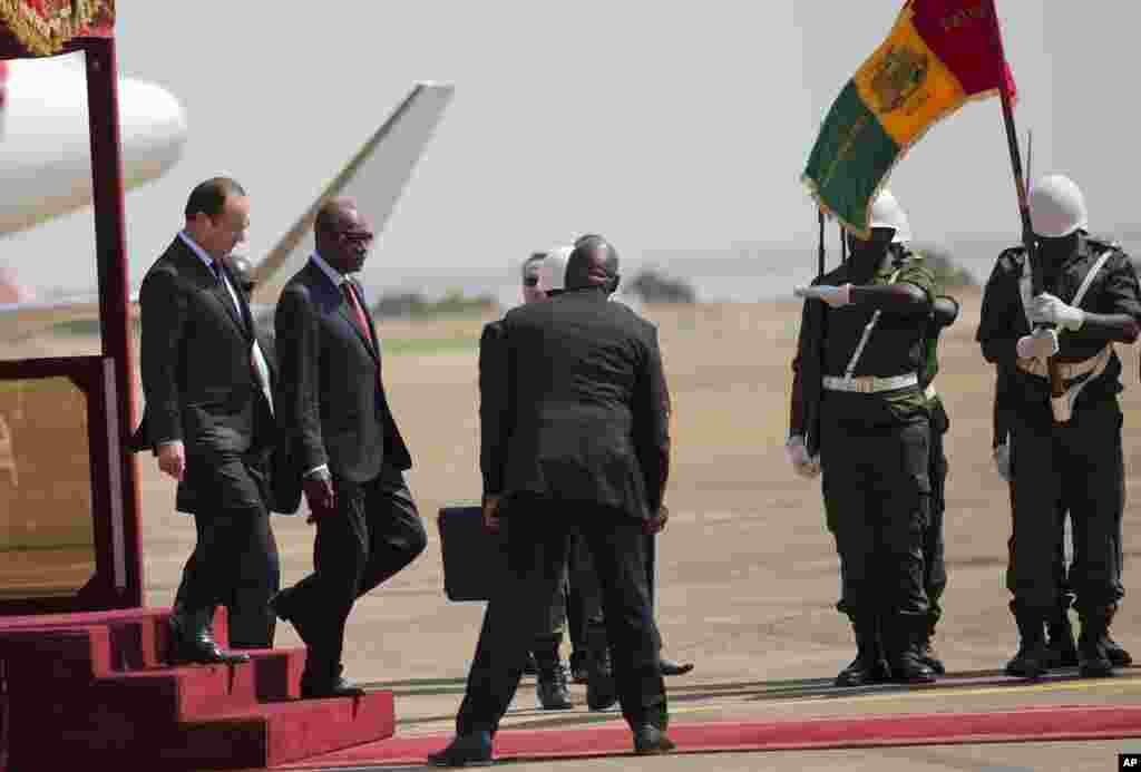 French President Francois Hollande, left, and his Guinean counterpart Alpha Conde review the honor guard, in Conakry, Guinea, Friday, Nov. 28, 2014.