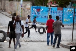 Supporters of presidential candidate Moise Jean-Charles move tires before burning them during protests against official results just announced by the Electoral Council in the neighborhood of Delmas 33, Port-au-Prince, Haiti, Nov. 5, 2015.