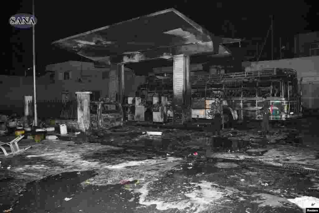 Men stand amidst wreckage and debris after a car bomb exploded at a crowded gas station in Barzeh al-Balad district in Damascus, in this handout photograph released by SANA on January 3, 2013. 