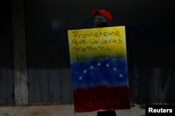 A demonstrator holding a rudimentary shield that reads "Promise me you will come back tomorrow. Venezuela", poses for a picture before a rally against Venezuelan President Nicolas Maduro's government in Caracas, Venezuela, June 17, 2017.