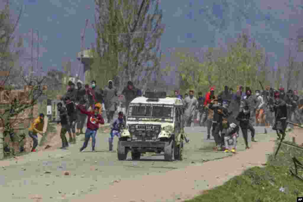 Kashmiri villagers throw stones and bricks at a police vehicle during a protest near the site of a gunbattle in Pulwama, south of Srinagar, Indian-controlled Kashmir.