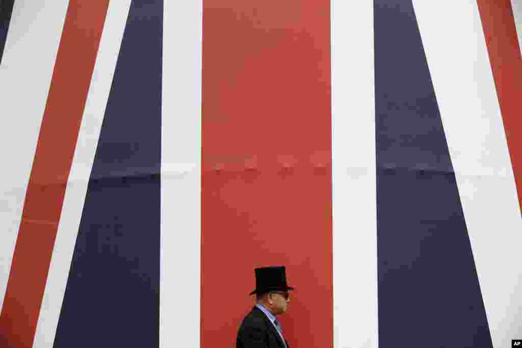 A racegoer walks past a huge British flag during the second day of the Royal Ascot horse race meeting in Ascot, England.