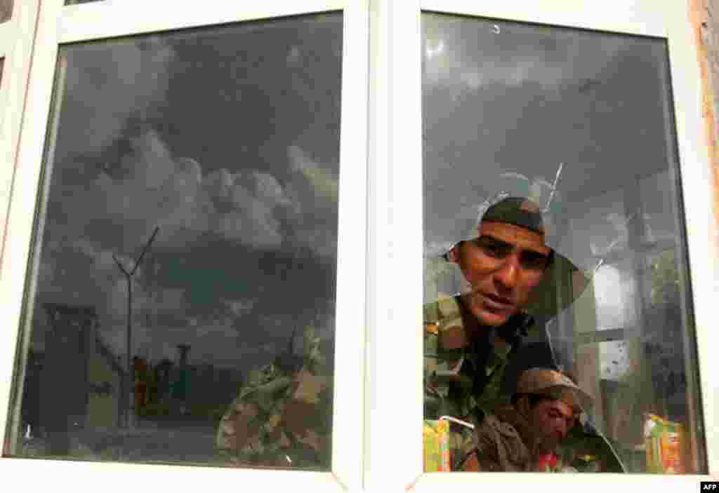 A former soldier of Muammar Gaddafi looks through a broken window inside a military compound in Benghazi. (Reuters/Suhaib Salem)