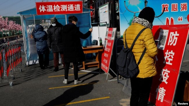 北京市民在进入一个市场前用手机刷健康码。(2021年1月11日)