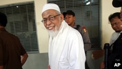 Militant cleric Abu Bakar Bashir walks from inside a holding cell to the start of his trial at a district court in Jakarta, Indonesia, June 6, 2011.