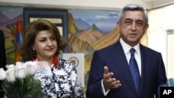 Armenian President and Republican Party President Serzh Sarkisian speaks to press after he voted during parliamentary elections in Yerevan, Armenia on Sunday, May 6, 2012. President's wife Rita Sarkisian smiles at left.