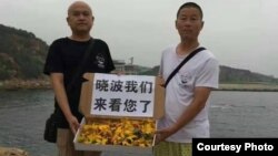 7月17日，大连维权人士姜建军（右）、王承刚前往大连老虎滩海边祭奠刘晓波。（推特图片）