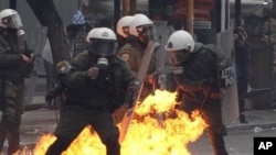 A petrol bomb explodes among riot police during clashes with protesters in Athens, 15 Dec 2010