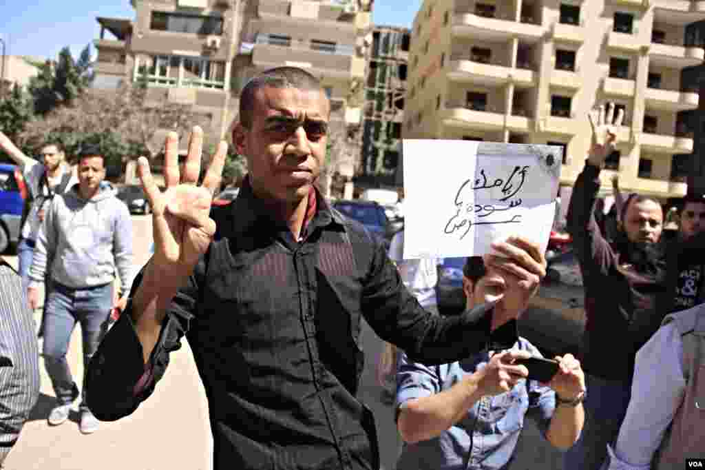A protester holds up four-fingers, a hand sign in memory of last year's deadly crackdown on supporters of ousted President Mohamed Morsi, Cairo, March 28, 2014. (Hamada Elrassam/VOA)