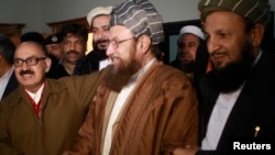 Maulana Sami ul-Haq (front C), one of the Taliban negotiators, and Irfan Siddiqui (front L), a government negotiator, shake hands after a news conference in Islamabad on February 6, 2014.