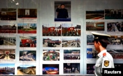 FILE - A paramilitary policeman looks at photos of North Korean leader Kim Jong Un and other North Korea-related images outside the North Korean Embassy in Beijing, Sept. 6, 2012. At the time, an official of a major Chinese investor said China should not be encouraging its companies to invest in reclusive North Korea because it still lacked the conditions to protect foreign investors.