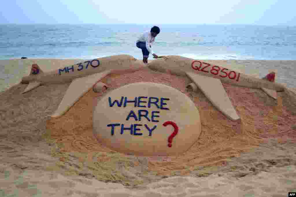 Indian sand artist Sudarsan Pattnaik finishes his sand sculpture of two missing aircraft, Air Asia QZ8501 and Malaysia Airlines MH370, on Golden Sea Beach at Puri, some 65 kilometers east of Bhubaneswar.