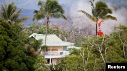 Smoke and lava erupt from a fissure near a home on the outskirts of Pahoa during ongoing eruptions of the Kilauea Volcano in Hawaii, May 14, 2018.