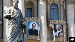 The tapestries of Roman Catholic Archbishop Oscar Romero, left, and Pope Paul VI hang from a balcony of the facade of St. Peter's Basilica at the Vatican, Oct. 13, 2018. Pope Francis will canonize two of the most important and contested figures of the 20th-century Catholic Church Sunday.