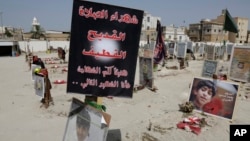 FILE - Religious flags, photographs and tributes to 21 victims of a suicide bombing of a Shi'ite mosque are displayed at a cemetery in al-Qudeeh, Saudi Arabia, May 30, 2015.