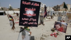 FILE - Religious flags, photographs and tributes to victims of a suicide bombing of a Shi'ite mosque are displayed at a cemetery in al-Qudeeh, Saudi Arabia, May 30, 2015.