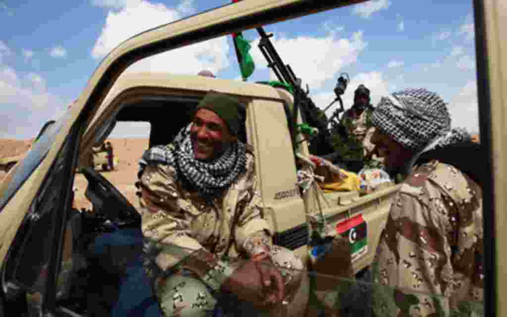 Rebel fighters in a vehicle mounted with a anti-aircraft gun relax as they wait for their convoy to move out after refuelling at a staging post on the western outskirts of Ajdabiyah April 1, 2011. REUTERS/Andrew Winning (LIBYA - Tags: CONFLICT MILITARY)